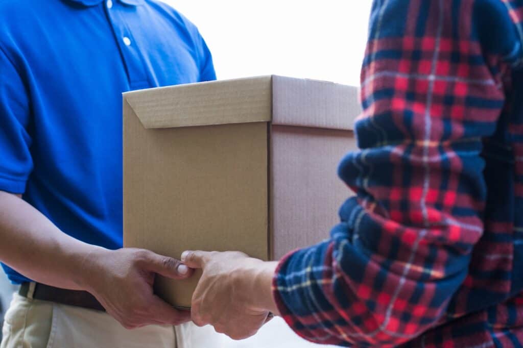 A man and van is handing a carton to the customer in the concept of a good man and van in Weymouth.