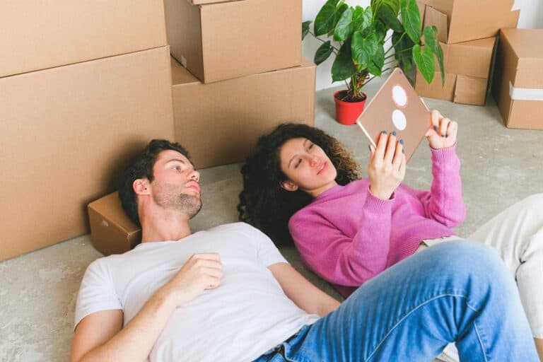 A young couple is relaxing on the floor after packing for their move to Weymouth.